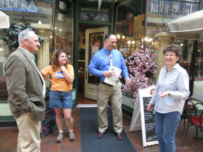 Paddock Arcade business owners, patrons, and friends have built a strong community in connection to the space. (l. to r.) Steve Duffany and Robyn Bartlett, who both have businesses in the Paddock Arcade, visit with friend Jason White, and with Carol Loch from Watertown, NY's Downtown Business Association. Photo by Camilla Ammirati, 2017.